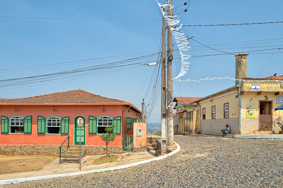 Casas coloniais coloridas numa rua de pedra em Lavras Novas, com bandeirinhas ao vento